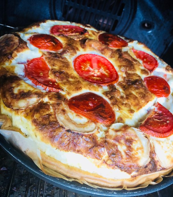 Quiche tomate et chèvre quiche bien dorée dans un moule à la sortie du four avec rondelles de tomate sur le dessus