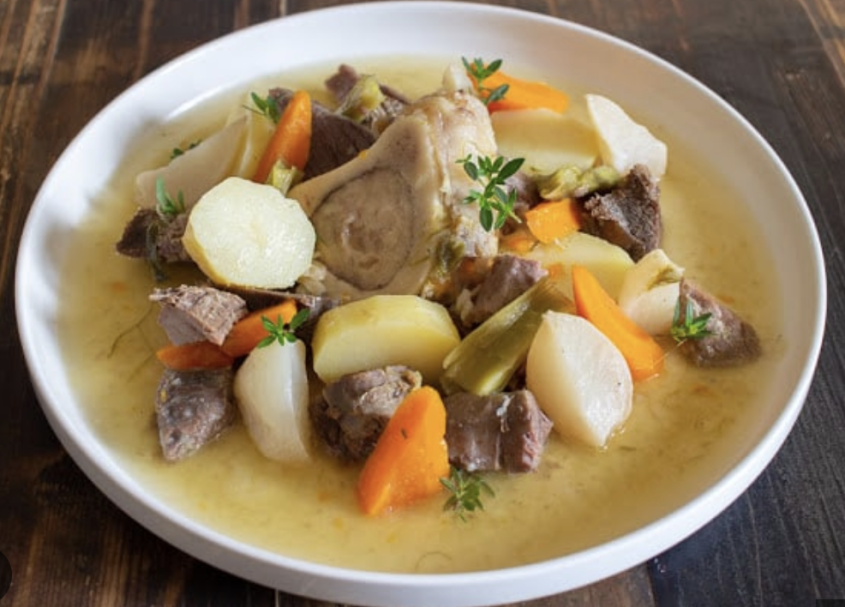 Pot au feu pot au feu présenté sur une assiette blanche: morceaux de viande, os à moëlle, rondelles pommes de terre, carotte, navet et bouillon