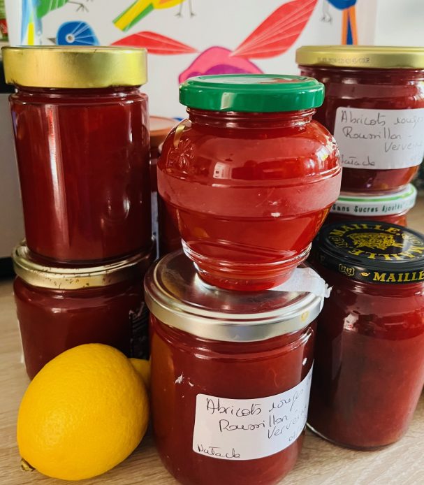 confitures plusieurs pots de confiture d'abricot empilés sur le plan de travail d'une cuisine. Les pots sont étiquetés et un citron est en décoration
