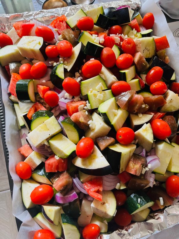 Ratatouille légumes d'été crus coupés en gros cubes sur une plaque de four et tomates cerise sur le dessus